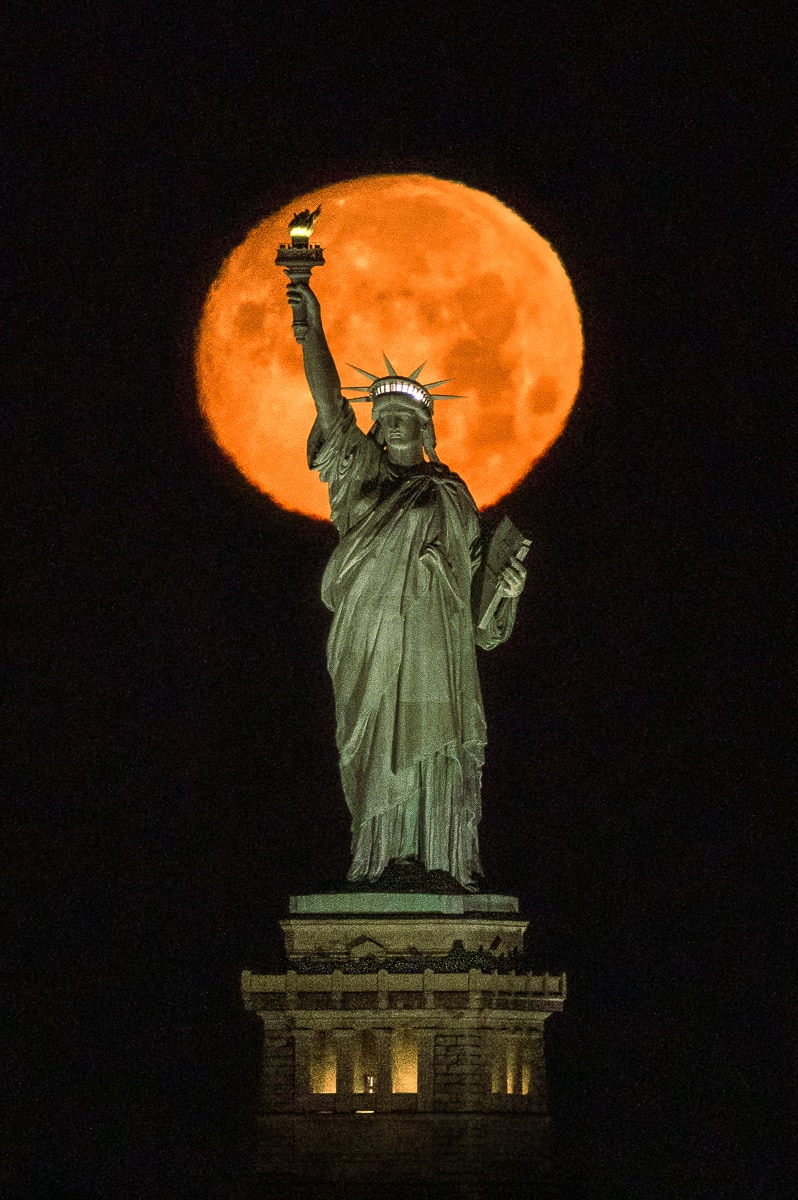 Moon rise behind the Statue of Liberty in New York